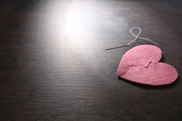 Heart cut in half and sewn back together on dark background. Relationship problems — Stock Photo, Image