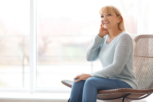 Retrato de una hermosa mujer madura sentada en un sillón en casa — Foto de Stock