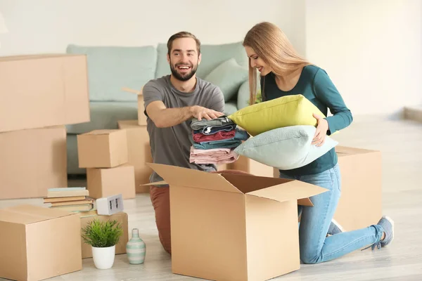 Casal jovem embalando caixas móveis no quarto — Fotografia de Stock