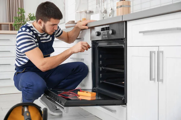 Młody mężczyzna naprawa piekarnika w kuchni — Zdjęcie stockowe