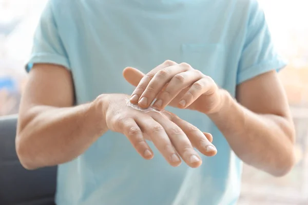Man applying hand cream at home, closeup — Stock Photo, Image