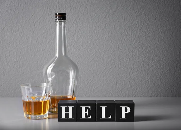 Strong drink and cubes with word HELP on table. Concept of alcoholism — Stock Photo, Image