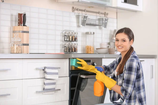 Молодая женщина уборка духовка на кухне — стоковое фото