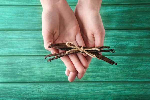 Woman holding vanilla sticks on wooden background — Stock Photo, Image