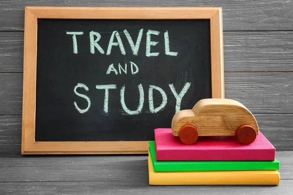 黑板上有 "旅行和学习"、汽车模型和桌子上的书栈。国外教育 — 图库照片