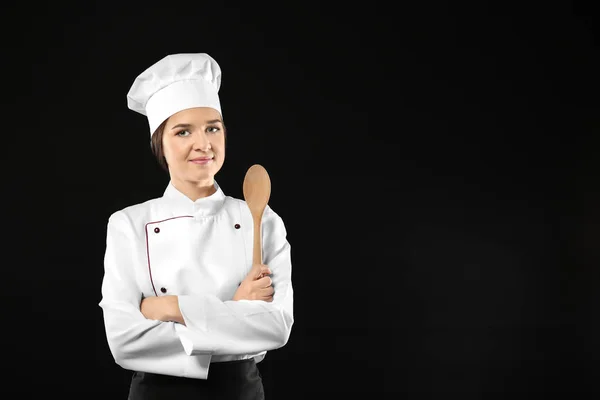 Retrato de chef femenina con cuchara de madera sobre fondo negro — Foto de Stock