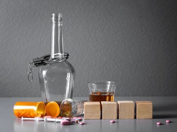 Strong drink, drugs, handcuffs and cubes with space for text on table. Concept of alcoholism — Stock Photo, Image