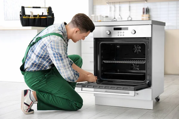 Anak muda memperbaiki oven di dapur — Stok Foto