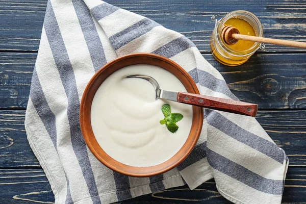 Lekkere yoghurt in de schotel en pot honing op houten tafel — Stockfoto