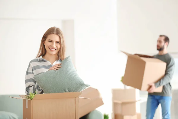 Young woman with moving box in room at new home — Stock Photo, Image