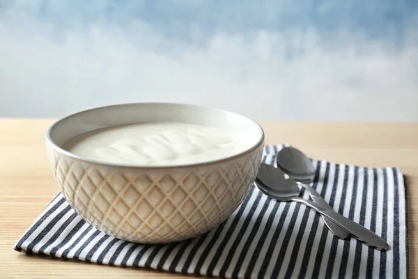 Tasty yogurt in dish on wooden table — Stock Photo, Image