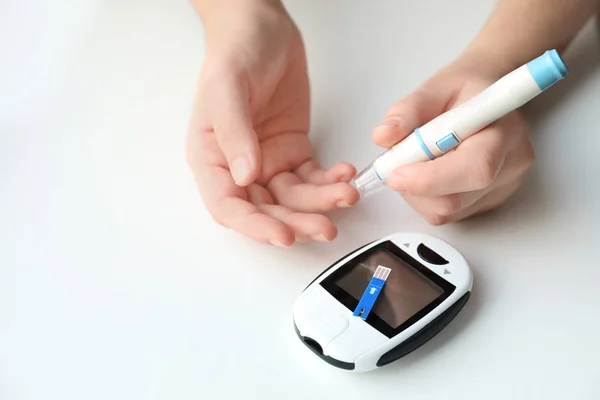 Woman using lancet pen on light background. Diabetes monitoring — Stock Photo, Image