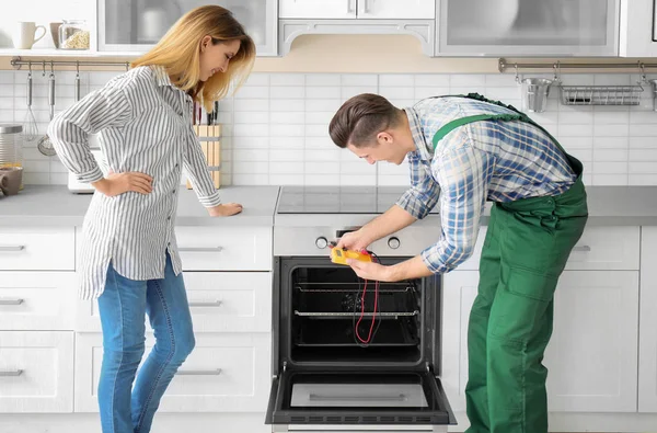 Husmor med arbeider i nærheten av ovn på kjøkkenet – stockfoto