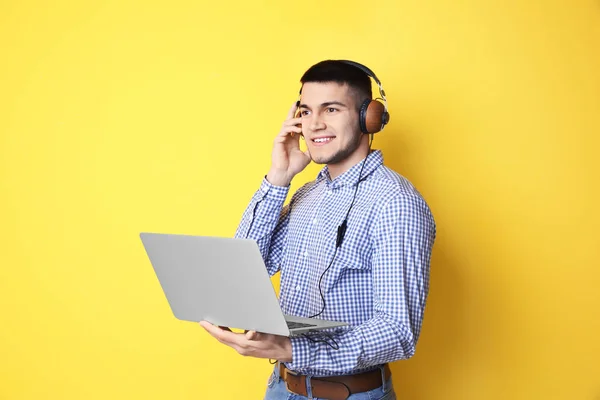 Man listening to audiobook through headphones on color background — Stock Photo, Image