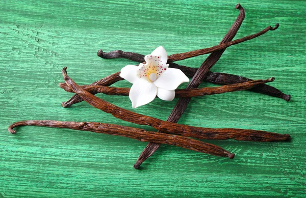 Vanilla sticks and flower on wooden background — Stock Photo, Image