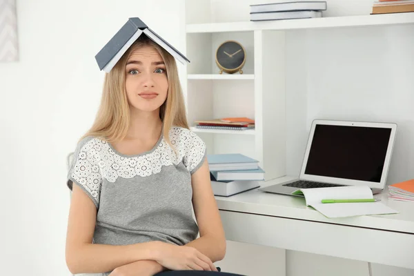 Étudiante avec un livre sur la tête à l'intérieur. Préparation à l'examen — Photo