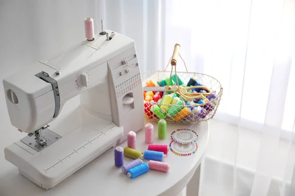 Modern sewing machine with threads on table — Stock Photo, Image