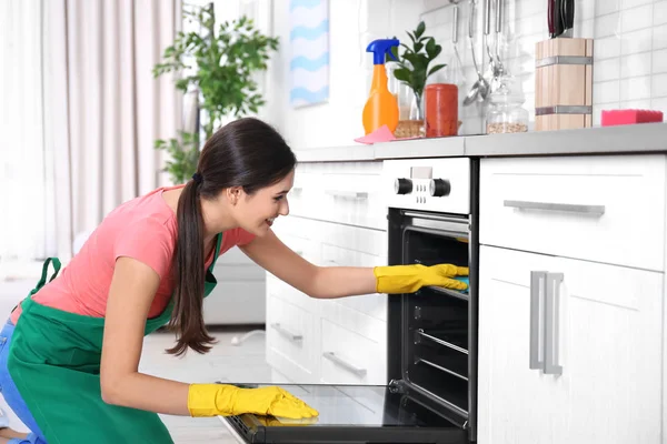 Young woman cleaning oven in kitchen — Stock Photo, Image