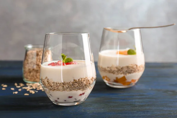 Yogurt with oat flakes in glasses on wooden table — Stock Photo, Image