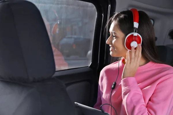 Mujer escuchando audiolibro a través de auriculares en el coche — Foto de Stock