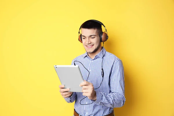 Homem ouvindo audiolivro através de fones de ouvido em fundo de cor — Fotografia de Stock