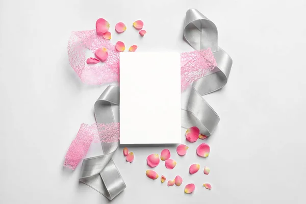 Pétalas de rosa, fitas e cartão vazio sobre fundo claro — Fotografia de Stock
