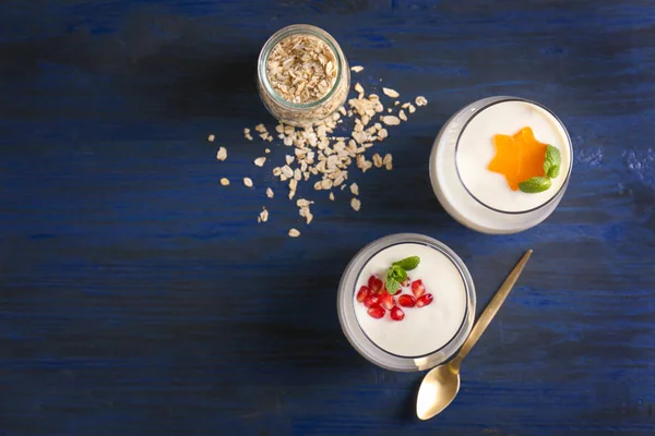 Yogurt con fiocchi d'avena in bicchieri su tavolo di legno — Foto Stock