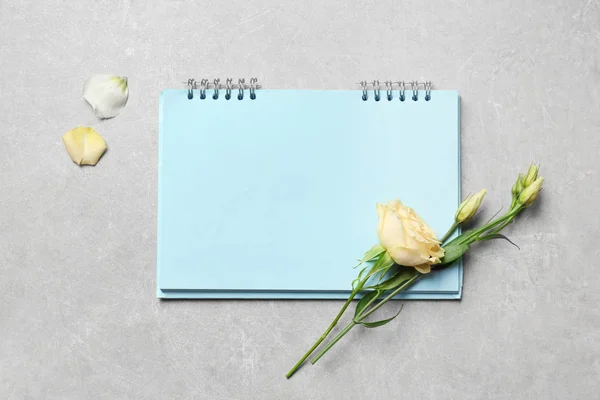 Λουλούδι και σημειωματάριο σε γκρίζο φόντο — Φωτογραφία Αρχείου