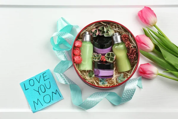 Cosmetic products in gift box, card with words "Love you mom" and tulips on light background. Mother's day celebration — Stock Photo, Image