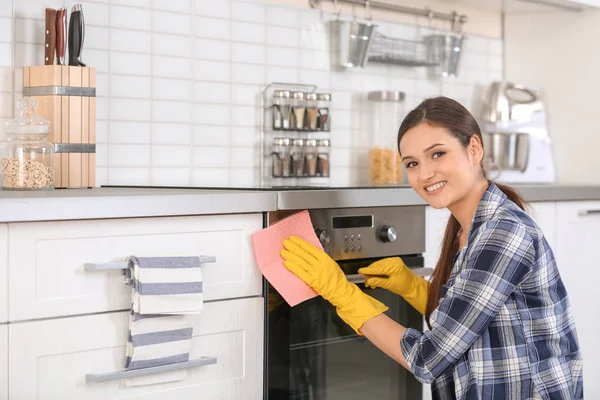 Young woman cleaning oven in kitchen — Stock Photo, Image