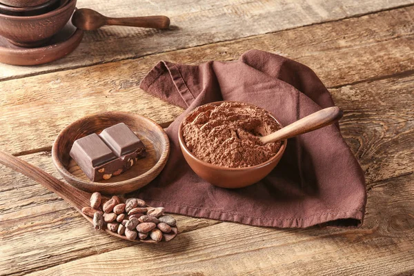 Chocolate saboroso, cacau em pó e feijão na mesa — Fotografia de Stock