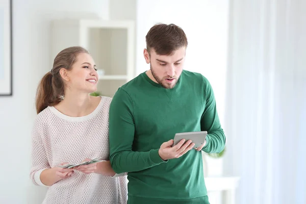 Glückliche Frau mit Geld und verwirrter Mann mit Taschenrechner zu Hause. Beziehungsprobleme — Stockfoto