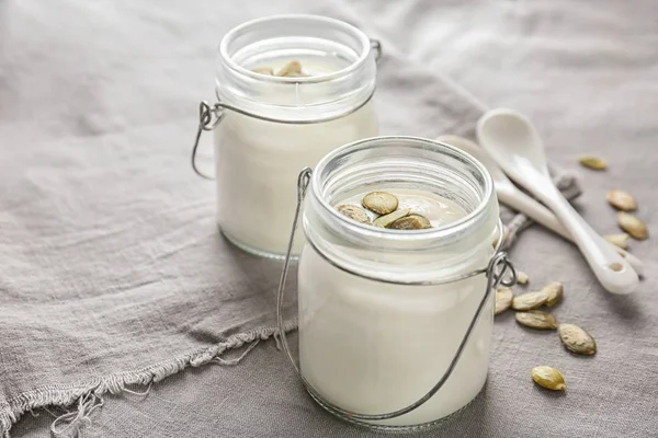 Yoghurt met pompoenpitten in potten op stof — Stockfoto