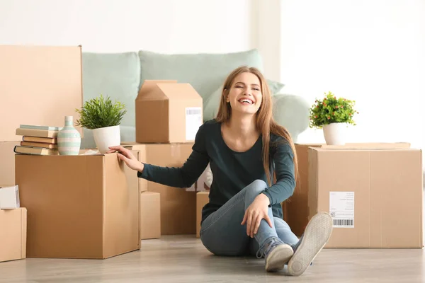 Jonge vrouw met bewegende vakken in de kamer op nieuw huis — Stockfoto