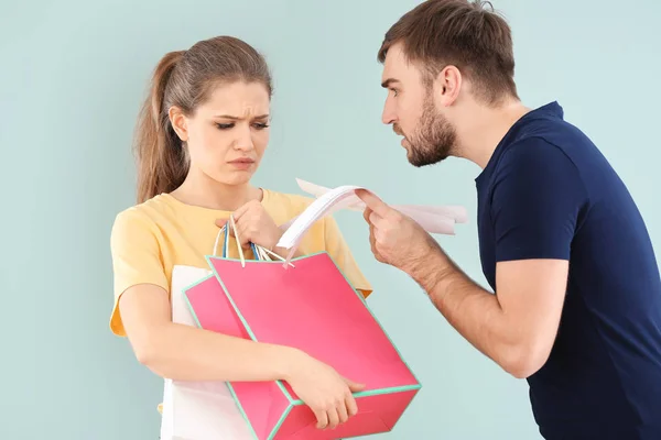 Vrouw met boodschappentassen en man met rekeningen ruzie over geld op kleur achtergrond. Problemen in relatie — Stockfoto