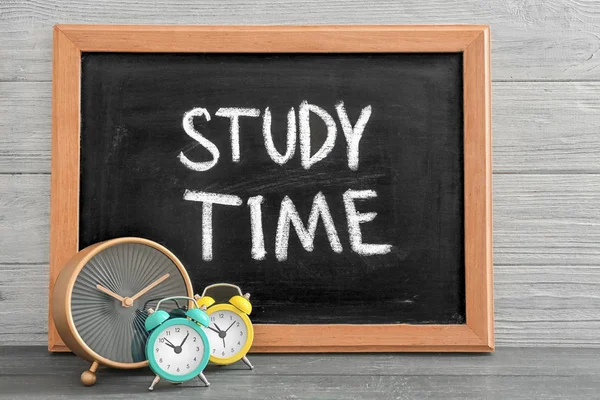 Chalkboard com frase "Tempo de estudo" e despertadores na mesa — Fotografia de Stock