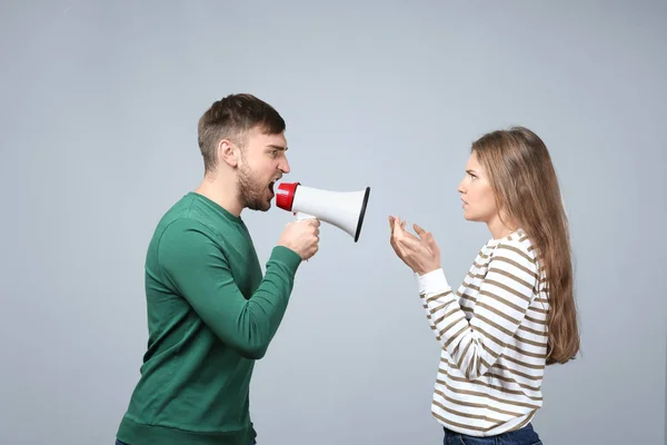 Jonge man schreeuwen in Megafoon op vrouw op lichte achtergrond. Problemen in relatie — Stockfoto
