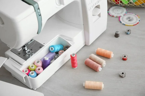 Machine à coudre moderne avec des fils sur la table — Photo