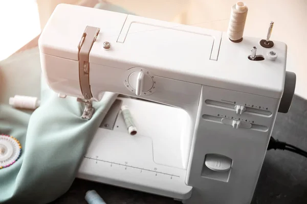 Modern sewing machine with fabric and threads on table — Stock Photo, Image