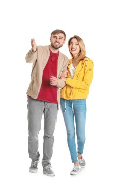 Beyaz arka planda yürüyen gündelik elbiseli genç bir çift.