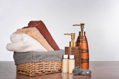 Hasır sepet ve temiz havlu ve tuvalet malzemeleri beyaz arka plan karşı ahşap tablo ayarlama