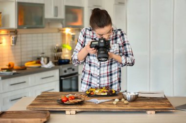 Genç kadın mutfakta natürmort fotoğraf çekmeye profesyonel kamera ile