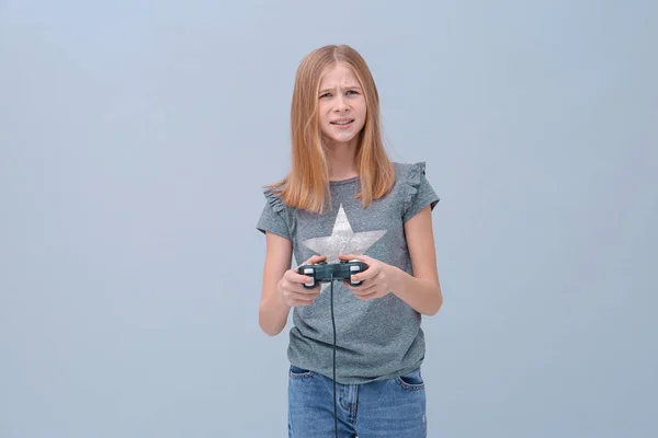 Emotionale Teenager-Mädchen mit Videospiel-Controller auf grauem Hintergrund — Stockfoto