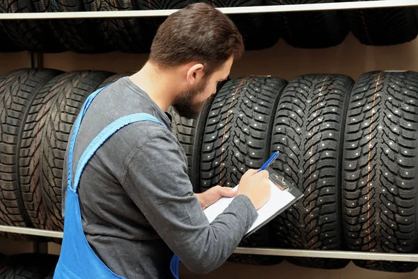 Verkäufer mit Klemmbrett nahe Reifen in Autohaus — Stockfoto