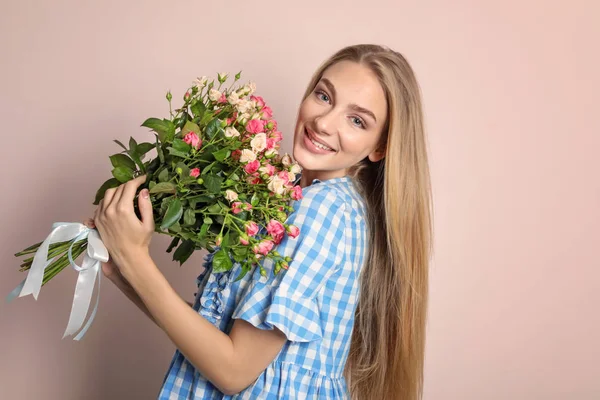 Красивая молодая женщина с букетом роз на цветном фоне — стоковое фото