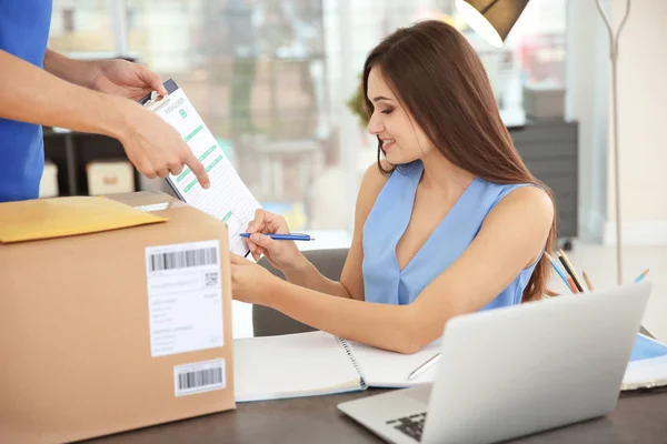 Woman signing documents after receiving parcel from courier — Stock Photo, Image