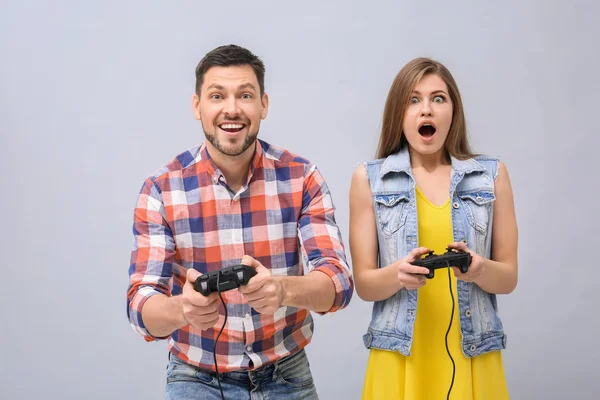 Emotionales Paar mit Videospiel-Controllern auf grauem Hintergrund — Stockfoto