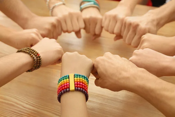 Group of people putting hands together over wooden table as symbol of unity — Stock Photo, Image