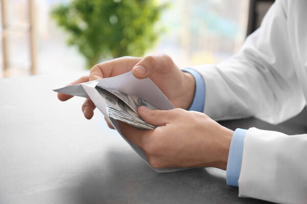 Доктор со взяткой на рабочем месте, крупным планом
