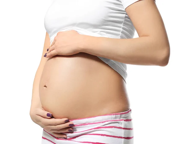 Pregnant woman in pajamas holding hands on belly against white background — Stock Photo, Image